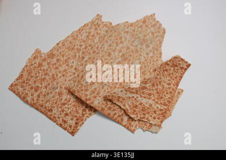 Close-up view of toasted brown matzo pieces from above. Light surface highlights subtle variations in color and form. Stock Photo