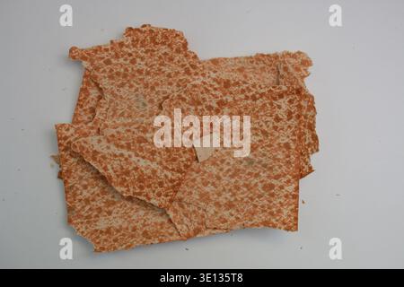 Rust-colored speckles dot the textured material. Close-up view of toasted brown matzo pieces from above. Stock Photo