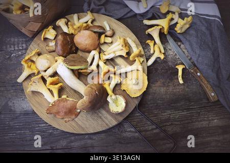 Mix of forest mushrooms on cutting board over old wooden table Stock Photo