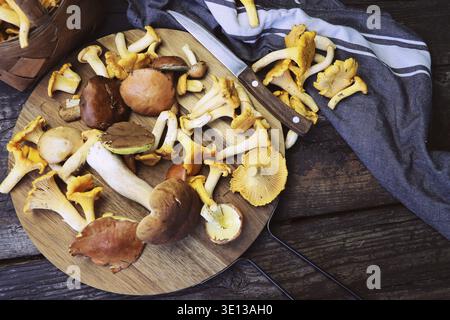 Mix of forest mushrooms on cutting board over old wooden table Stock Photo