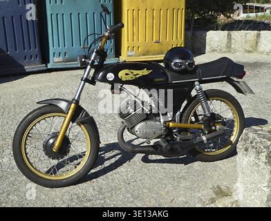 Custom vintage black motorcycle with gold details and flames sticker parked on cobblestone Stock Photo