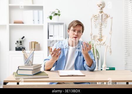 Teacher giving anatomy lesson in classroom with human skeleton model Stock Photo