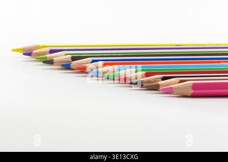 Sharpened multicolor pencils arranged in a diagonal row on clean white background, ideal for education and creativity concepts. Stock Photo