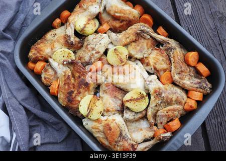 Roasted Rabbit Haunches in Pan with Stewed Vegetables on Rustic Wooden Table Surface Stock Photo