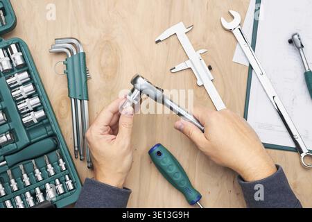Man working in workshop using many tools. Wrench, spanner, calliper and ratchet with many attachments. Work tools. Universal tool set. Professional eq Stock Photo