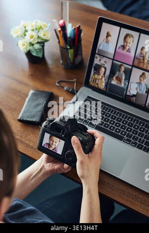 Female photographer working on photos on laptop and camera. Woman editing retouching browsing photos working as a freelancer sitting at desk Stock Photo