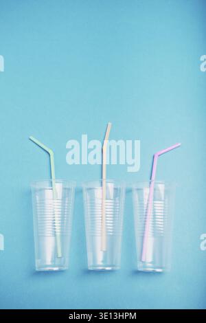 Empty plastic cups with colorful straws in a row over blue background. Collecting plastic waste to recycling. Concept of plastic pollution and too man Stock Photo