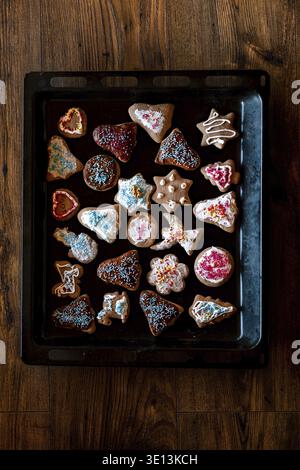Christmas gingerbread cookies in many shapes decorated with colorful frosting, sprinkle, icing, chocolate coating, toppers, put on tray Stock Photo