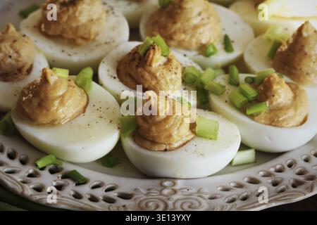 Deviled eggs with cod livers with leek on white plate. Rustic wooden table Stock Photo