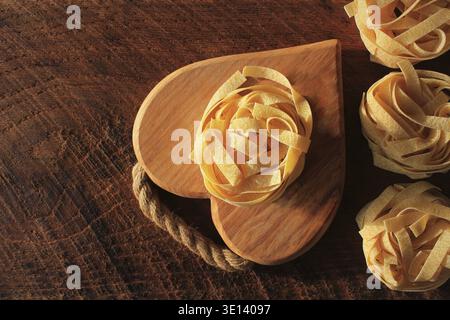 Raw tagliatelle pasta on wooden cutting board. Handmade italian traditional pasta Stock Photo