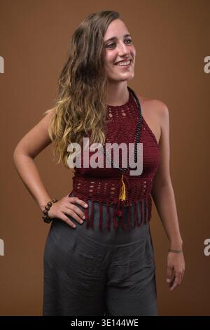 Studio shot of young beautiful Hispanic woman against brown background Stock Photo