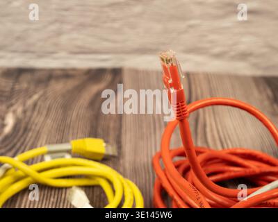 Macro shot of an orange Cat5 ethernet cable connector with a blurry background of yellow cables, focusing on connectivity. Stock Photo
