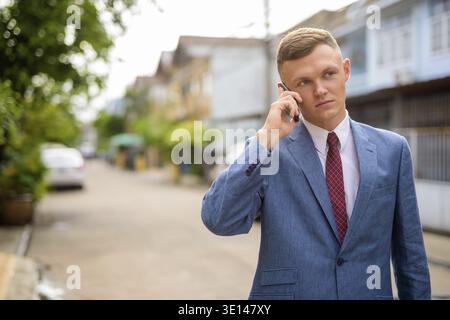 Portrait of young businessman using mobile phone in the streets outdoors Stock Photo
