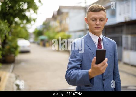 Portrait of young businessman using mobile phone in the streets outdoors Stock Photo