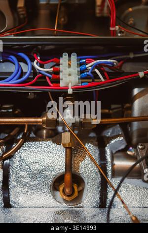 Wires in blue, red, and white connect to metal parts of the engine. The scene shows a detailed close-up of the internal workings of a machine in a wor Stock Photo