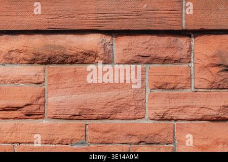 Close-up of red sandstone brick wall with rough textured surface and natural variation Stock Photo