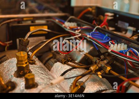 Various wires and metal parts connect in a mechanical system inside a workshop. Tools and equipment are visible in the background showing an active wo Stock Photo