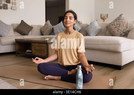 Woman meditating on yoga mat at home Stock Photo
