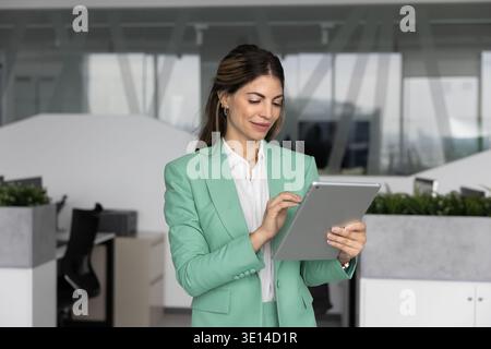 Hispanic female executive typing on digital tablet at modern office Stock Photo