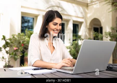 Happy young Latin freelancer woman working on online business project Stock Photo