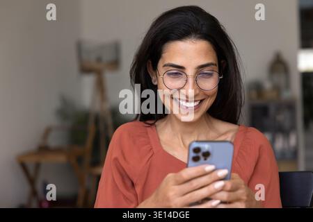 Happy Brazilian woman using smartphone at home Stock Photo