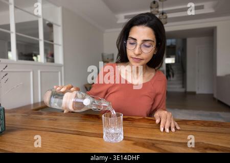 Young 30s woman pouring water into glass Stock Photo