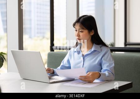 Employee sits at coworking desk preparing report, working on laptop Stock Photo