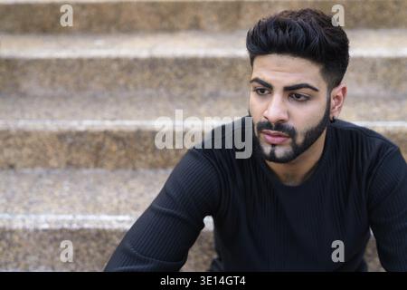 Young handsome Indian man sitting at stairs Stock Photo