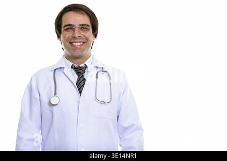 Studio shot of young happy Persian man doctor smiling while wearing eyeglasses Stock Photo