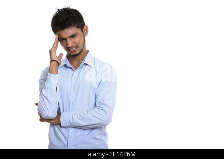 Studio shot of young stressed Indian man having headache isolated against white background Stock Photo