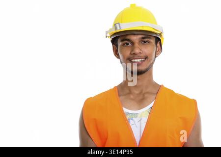 Studio shot of young happy Indian man construction worker smiling Stock Photo