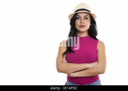Studio shot of young beautiful Spanish woman wearing hat with arms crossed Stock Photo