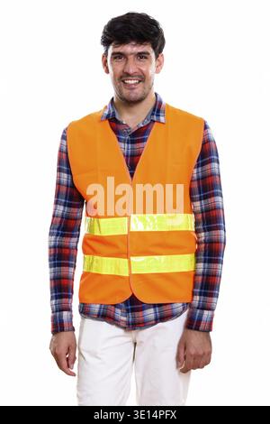 Studio shot of young happy Persian man construction worker smiling while standing Stock Photo