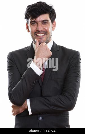 Studio shot of young happy Persian businessman smiling while thinking Stock Photo