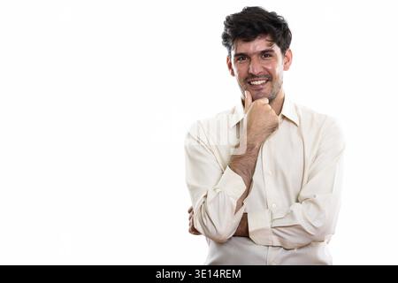 Studio shot of young happy Persian businessman smiling while thinking Stock Photo