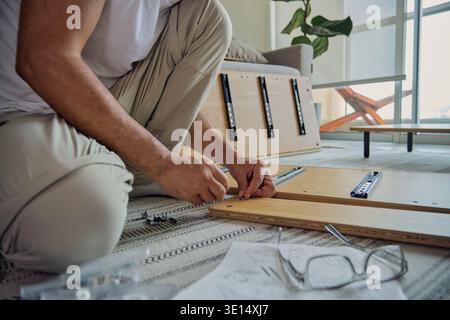 Man installing drawer slides on wooden furniture panel for home improvement project Stock Photo