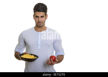 Young handsome Persian man holding bowl of potato chips and red apple Stock Photo