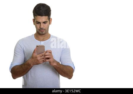 Young handsome Persian man using mobile phone isolated against white background Stock Photo