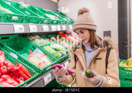 Woman counting calories on smartphone during grocery shopping Stock Photo