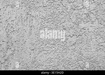 Close-up reveals how cement plaster application on concrete creates rough grainy texture with bumpy irregularities from troweling, selective focus Stock Photo