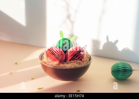 Paper Easter eggs with bunny ears in bowl in sunlight. Closeup. Stock Photo