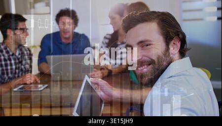 Reacting to data overlay, bearded man in collared shirt presenting at meeting table, holding tablet Stock Photo