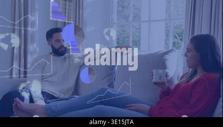 Discussing holographic charts, two adults on gray sofa at home in red sweater, holding white mug Stock Photo