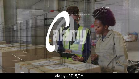 Checking warehouse workers in hi-vis vest and beige jacket, reviewing tablet on boxes with overlay Stock Photo