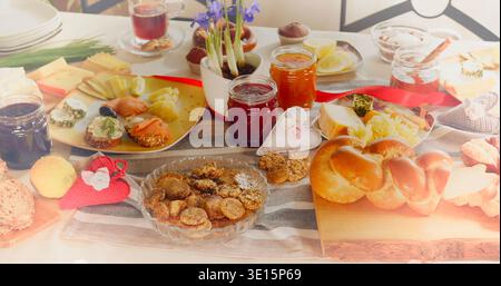 Different types of food and drinks served on a table during a gathering for friends and family in a home setting Stock Photo
