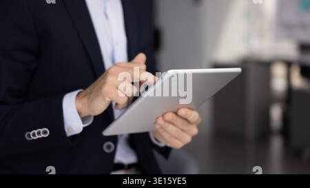 Closeup businessman in formal suit using digital tablet in office Stock Photo