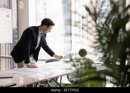 Mid aged businessman market researcher reading stats reports on desk Stock Photo