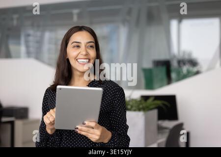 Cheerful Middle Eastern female professional using tablet pc in office Stock Photo