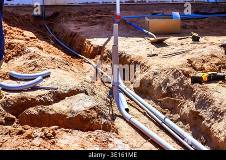 Workers are digging trench at construction site to install pipes for electrical in foundation of new building. Stock Photo