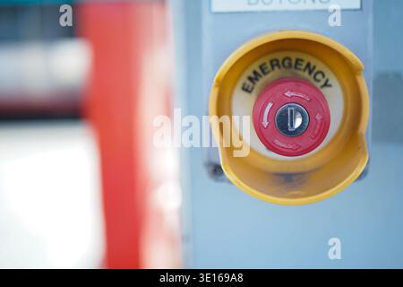 Red emergency button on a gray panel at a facility Stock Photo